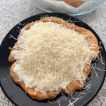 Az elkészült lángos recept, tejföllel és sajttal tálalva.